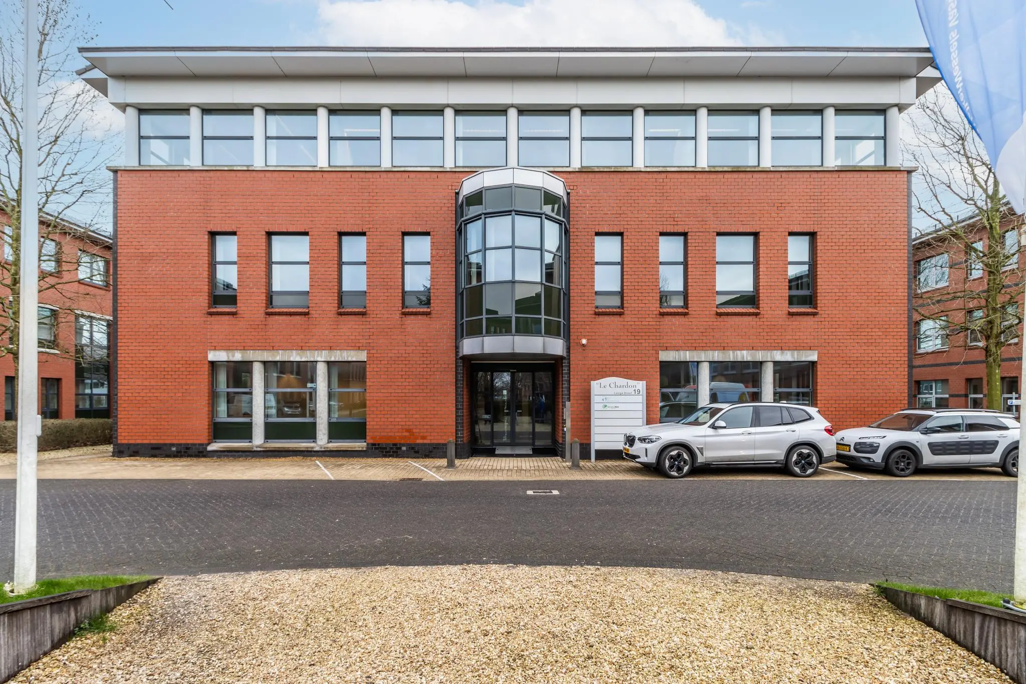Vooraanzicht van het kantoorgebouw "Le Chardon" aan de Lange Dreef, met geparkeerde auto's op de voorgrond.